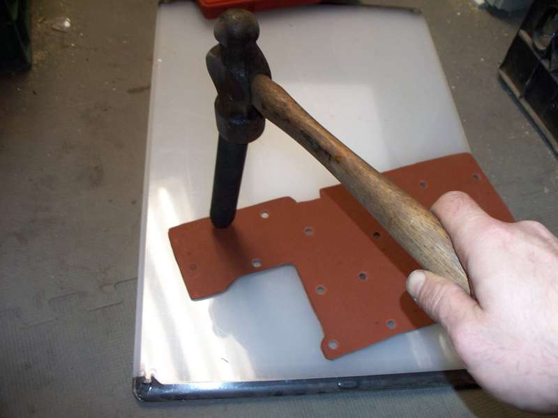 A hammer punching a hole in a gasket.